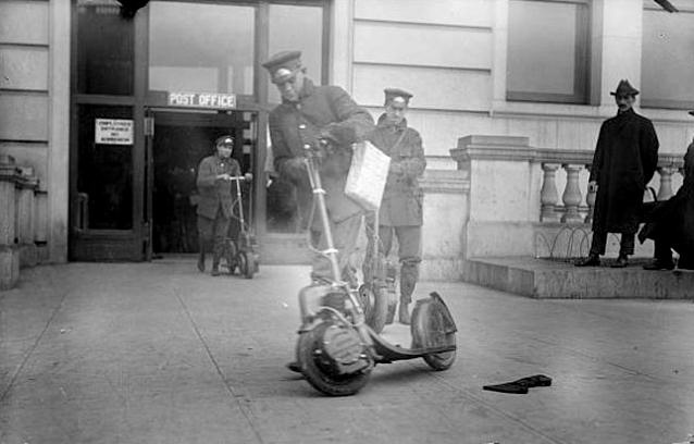 American postmen on Autoped come out of the post office